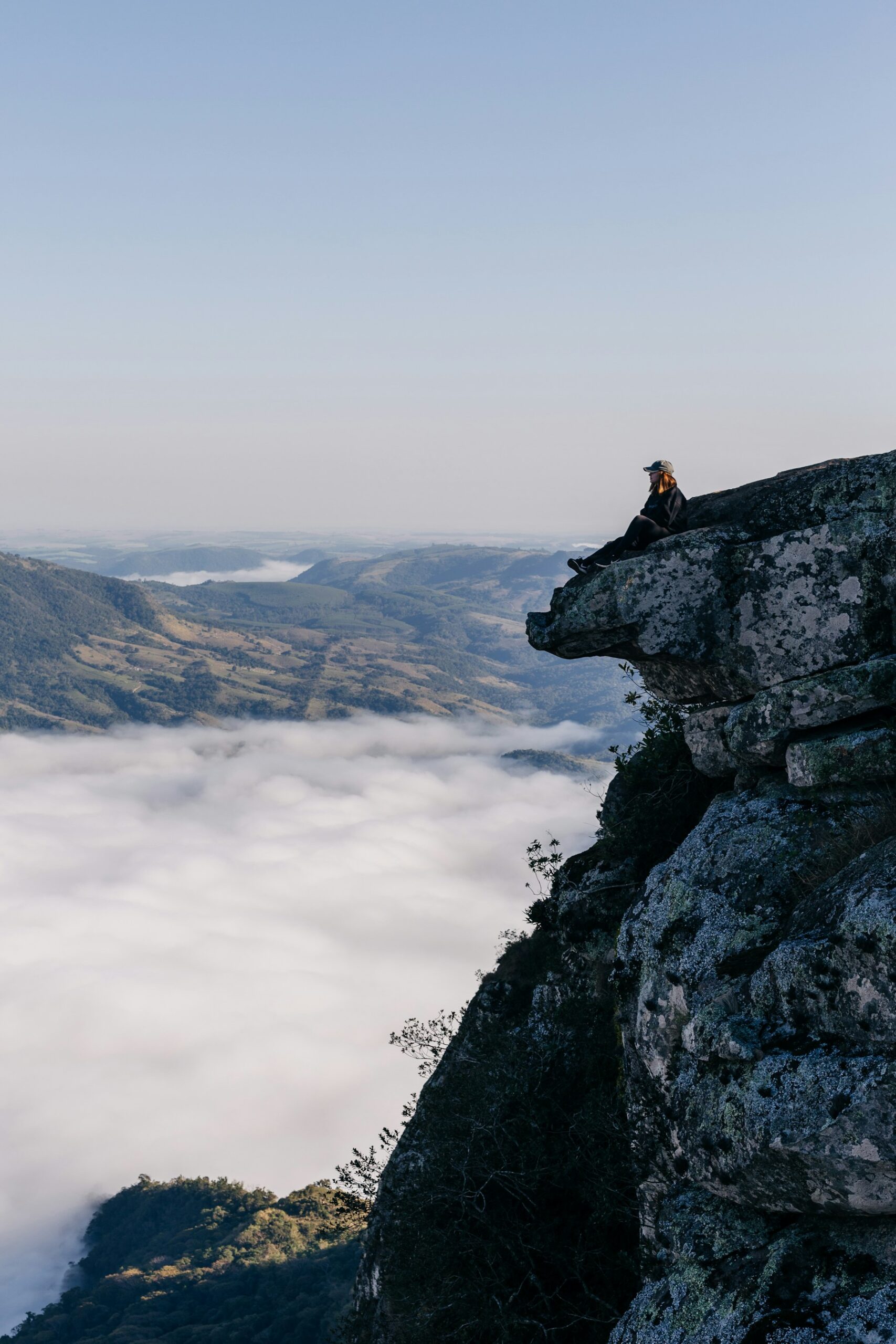 A person sitting on top of a cliff above the clouds